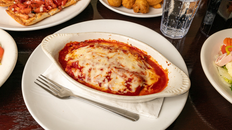 Manicotti on restaurant plate surrounded by other dishes