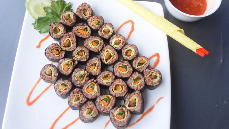 White serving plate filled with brown rice sushi rolls