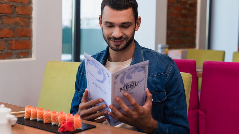 Man looks at menu in sushi restaurant