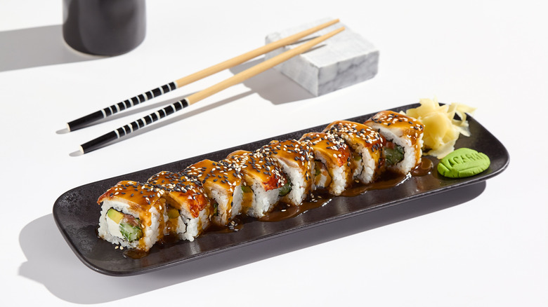 Unagi sushi roll drizzled with eel sauce on black serving plate