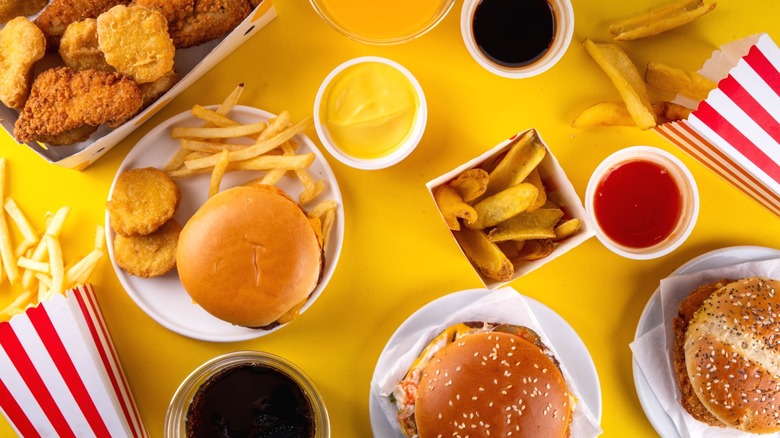 Various fast food items like nuggets, fries, burgers, chicken strips laid out on yellow surface