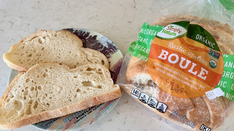 A bag of Simply Nature Organic Rustic Italian Boule bread with two slices on a plate