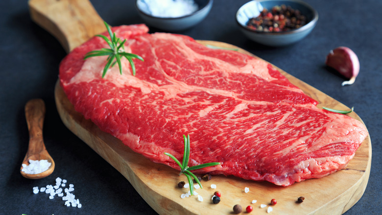 raw chuck steak on wooden board