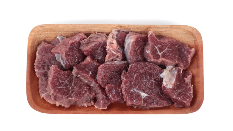 Raw cube steak, on wooden tray, white background, top view.