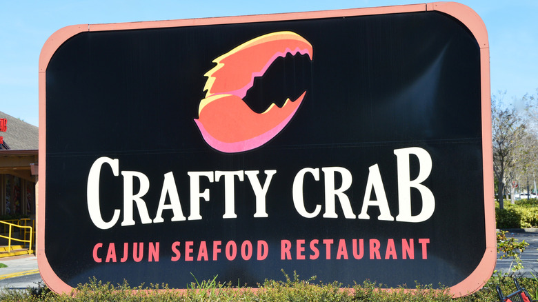 A sign for the Crafty Crab Cajun Seafood Restaurant with a crab claw symbol.