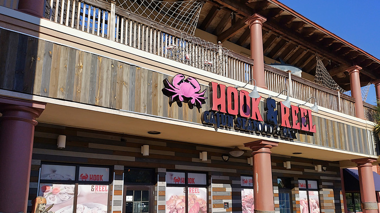 The outside of Hook & Reel Cajun Seafood with a crab symbol by the sign on the wood building.