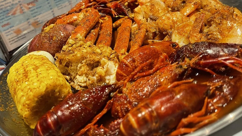 A plate full of lobster, corn, shrimp and crawfish.
