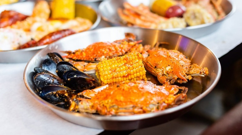 Soft shell crab and mussels in a silver dish with corn.