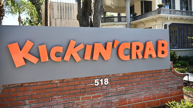 The outside sign for Kickin' Crab on a grey background with orange letters.