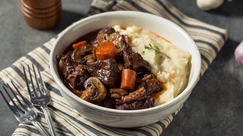 Beef bourguignon in bowl with mashed potatoes, with napkin and silverware