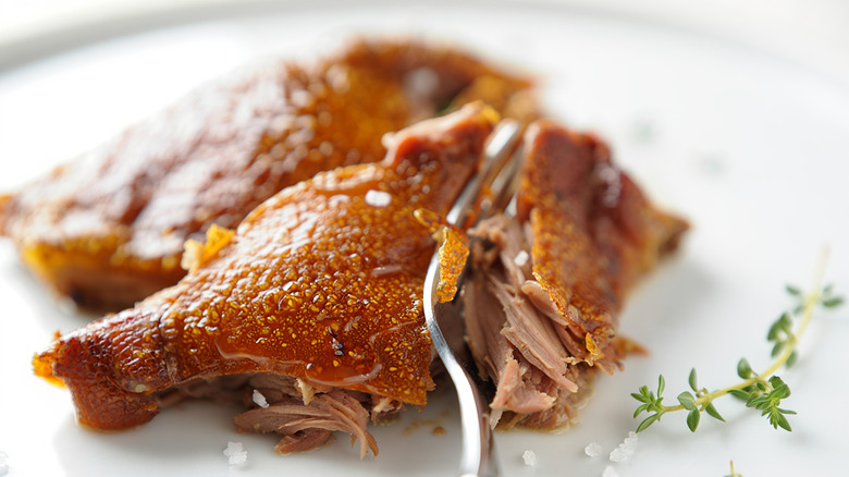 Fork cutting into duck on plate