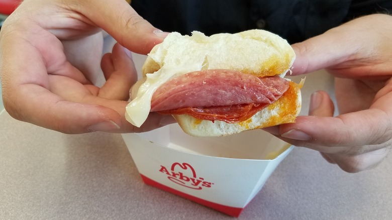 Hands hold an Arby's pizza slider