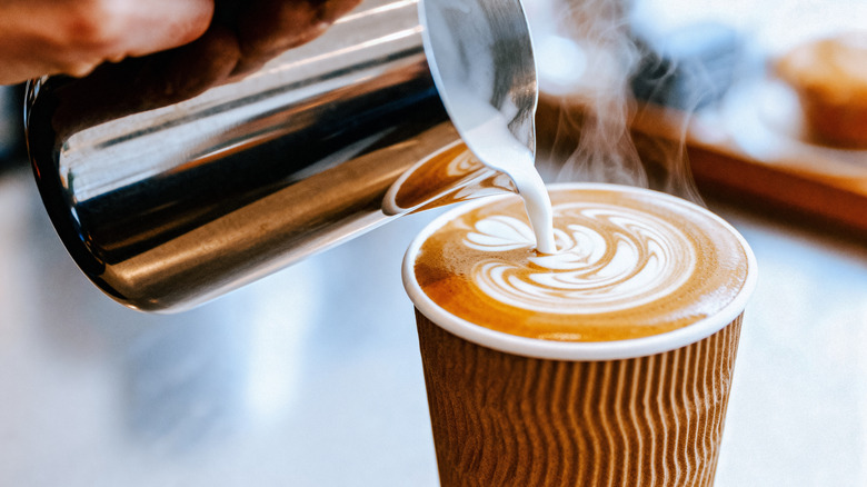 A barista pouring milk into a latte.