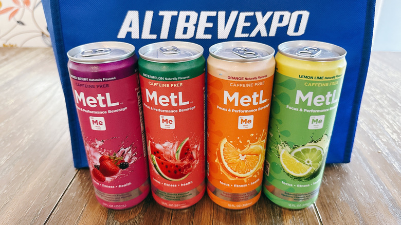 MetL cans on wooden table in front of a blue bag from the Alt Bev Expo