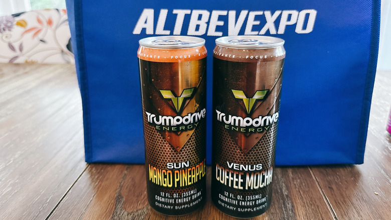 Trumpdrive cans on wooden table in front of a blue bag from the Alt Bev Expo