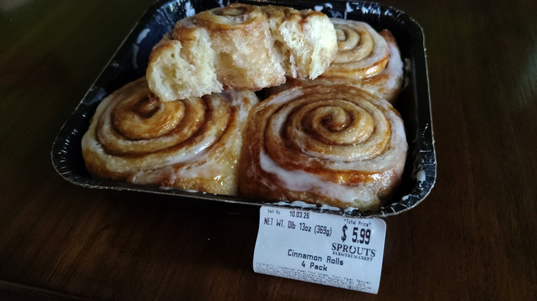 A four-pack of Sprouts bakery cinnamon rolls show very little cinnamon inside and very little glaze on the outside.