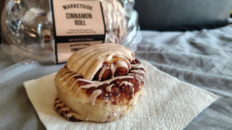 A Marketside cinnamon roll topped with frosting and drizzled with cinnamon icing.