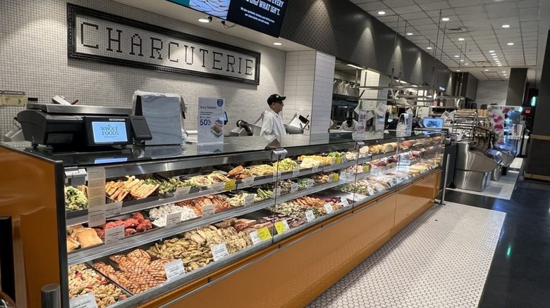 Charcuterie deli case counter at Whole Foods with sandwiches and cooked meats