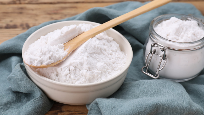 Bowl, spoon, and glass jar of natural starch on wooden table