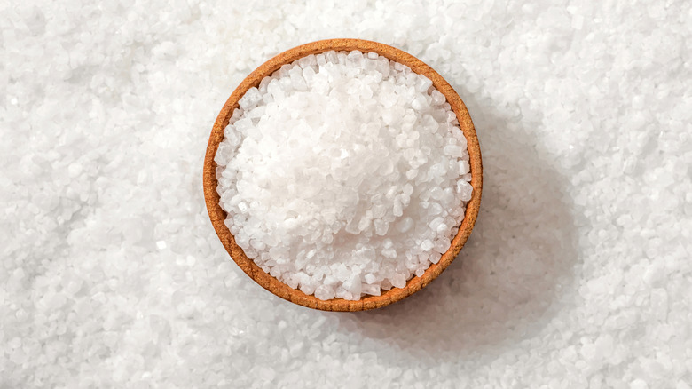 A wooden bowl of salt sitting on a bed of salt