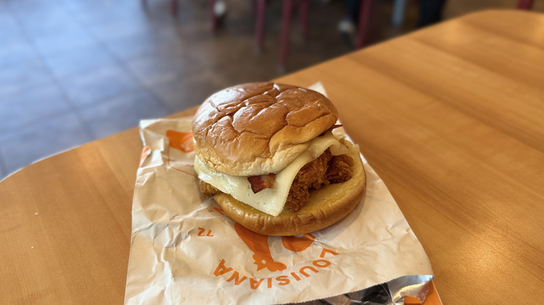 Popeyes Bacon & Cheese Chicken Sandwich with wrapping on a table