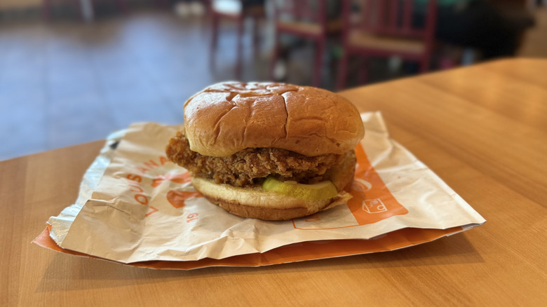 Popeyes Classic Chicken Sandwich with wrapper on a table