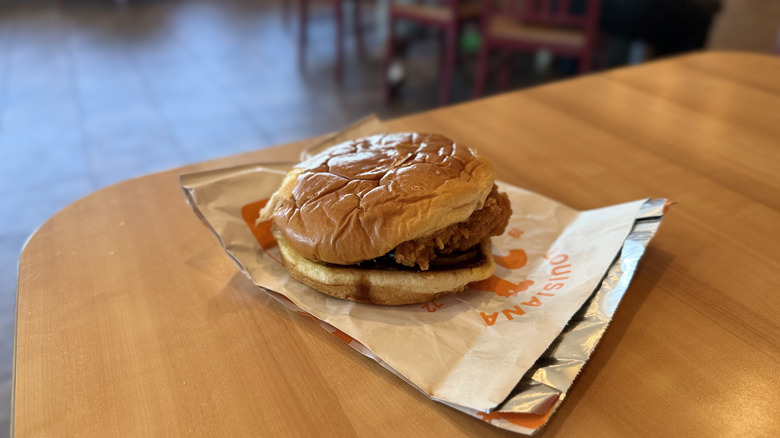 Popeyes Honey BBQ Chicken Sandwich with wrapper on a table