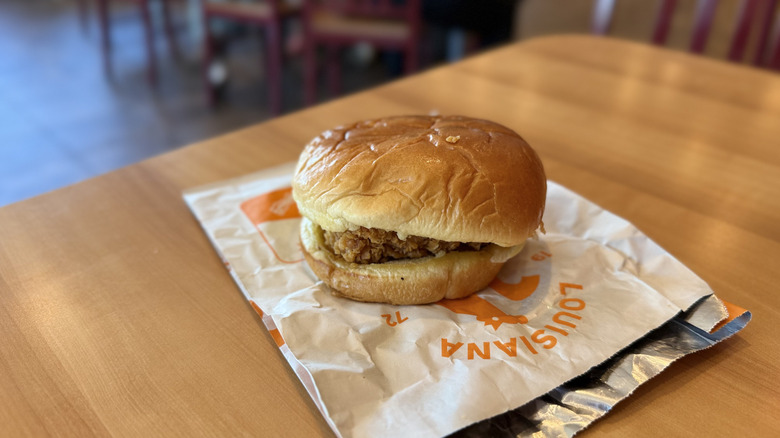 Popeyes Spicy Chicken Sandwich with wrapper on a table
