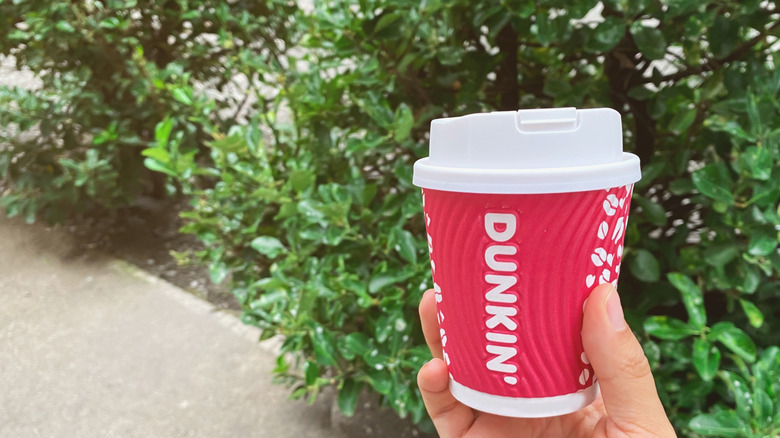 Hand holding red Dunkin' cup
