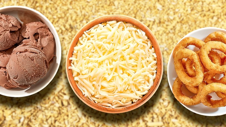 Bowls of ice cream, cheese, onion rings on beige background