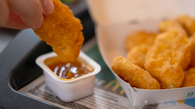 Mcnugget being dipped into sweet n' sour sauce