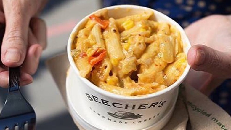 hands holding Beecher's Handmade Cheese mac and cheese with peppers