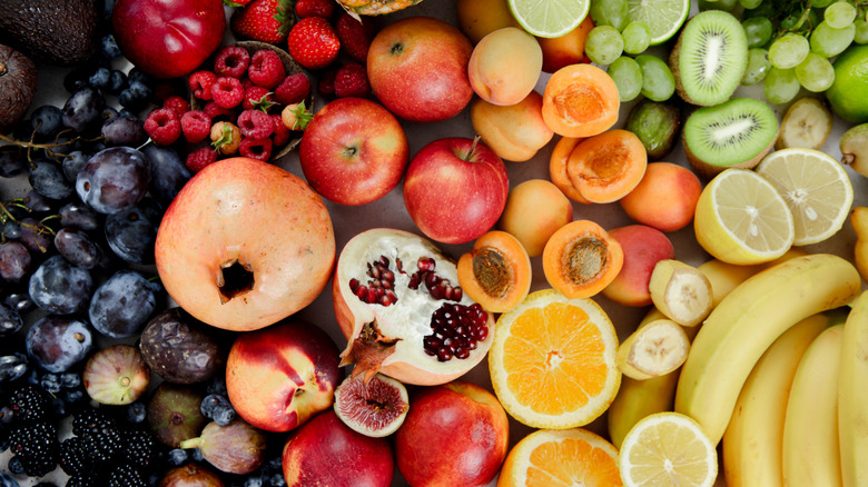 A hodgepodge of various fruits laid out on a table and sorted by color.