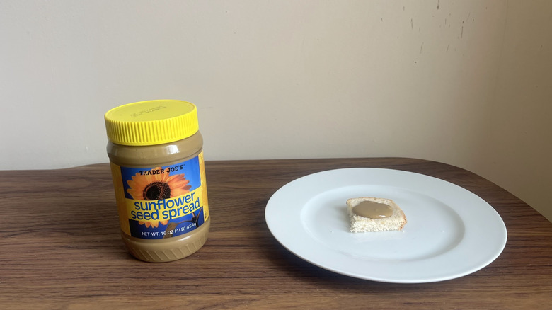 Jar of sunflower seed spread from Trader Joe's with small amount spread on a piece of bread on a round white plate