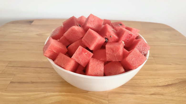 Watermelon cubes in white bowl on wooden table