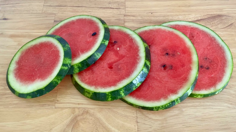 Five watermelon rounds displayed on wooden table