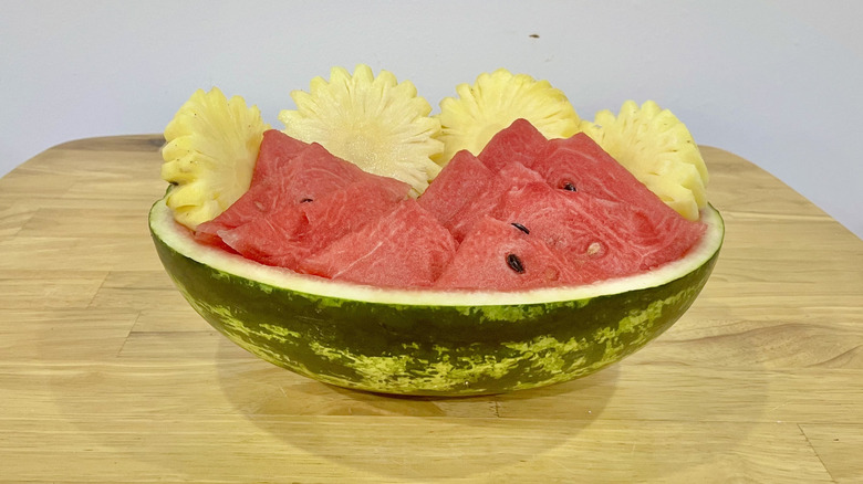 Hollowed watermelon boat with pineapple and watermelon wedges inside