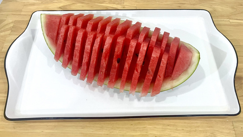 Thin wedges zig-zagged in quartered watermelon bowl on wooden table