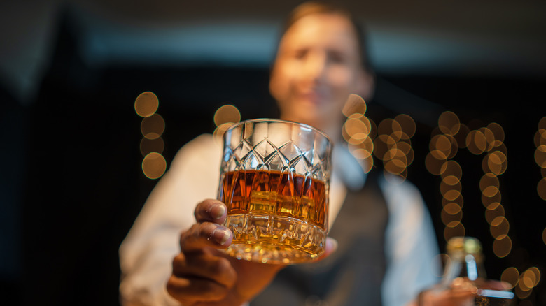 Blurred out bartender serving a glass of whiskey