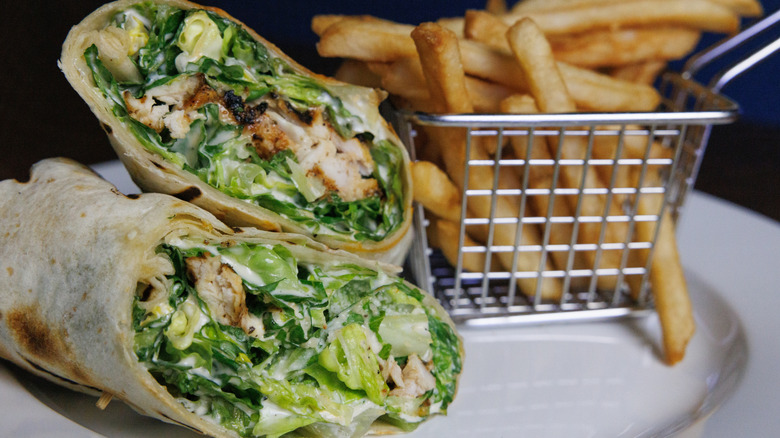Chicken Caesar salad wrap on plate with french fries