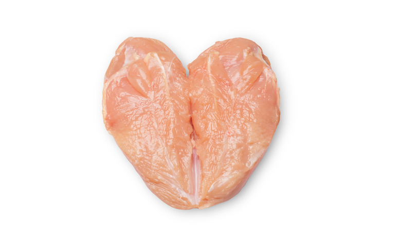 A raw chicken breast that's been butterflied on a white background