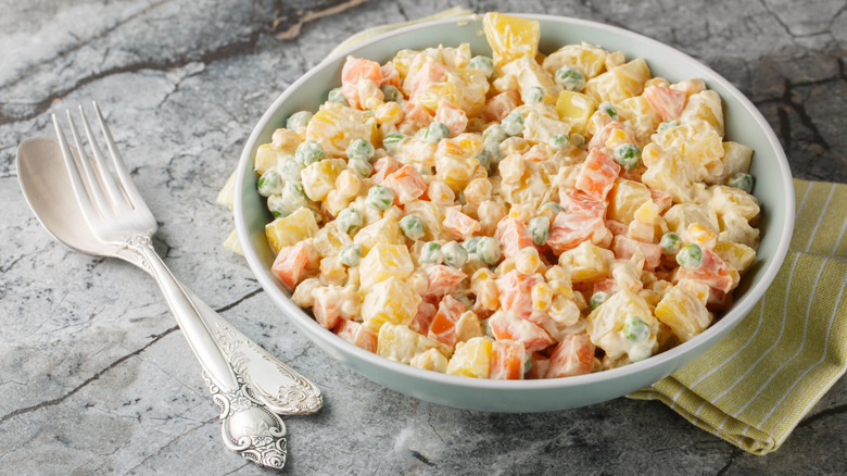 A bowl of salada de maionese on a stone countertop