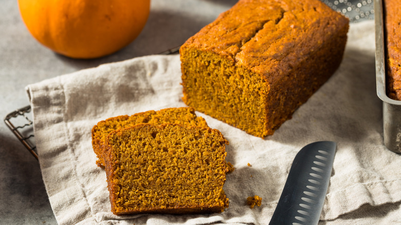 A sliced loaf of pumpkin bread on a greige towel