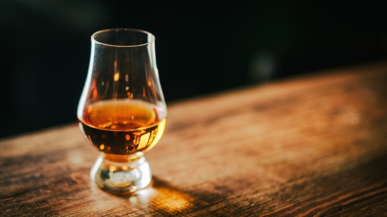 A glass of bourbon on a wood table