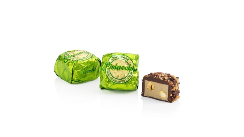 Two individually wrapped candies and one unwrapped half of a Venchi Chocoviar Pistachio chocolate