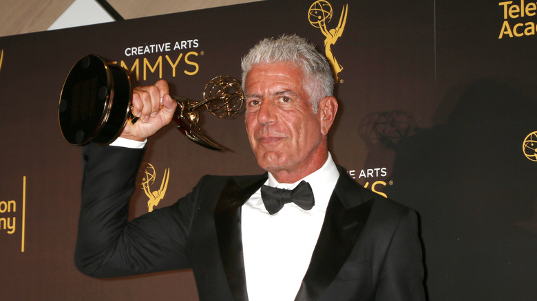 Anthony Bourdain holding up an Emmy award statue