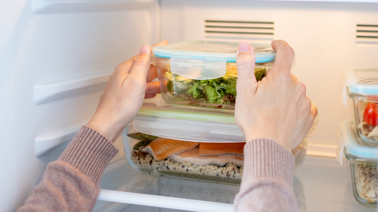 Person placing glass storage containers on a fridge shelf