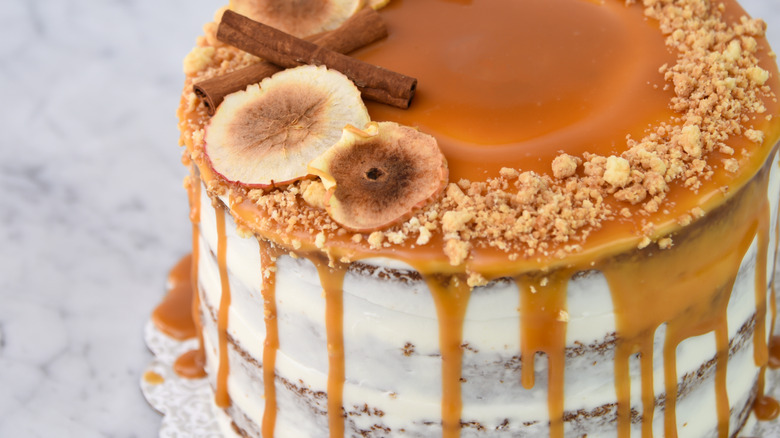 closeup of layer cake with caramel frosting on top and dried fruits and cinnamon sticks
