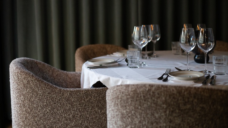 Upscale looking dining table with wine glasses, fabric chairs