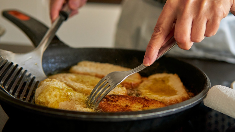 Woman preparing French toast in a pan with butter